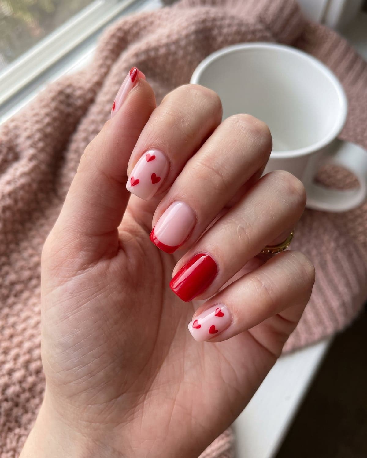 Red heart nail art on pink nails with a red micro French tip and solid red accent