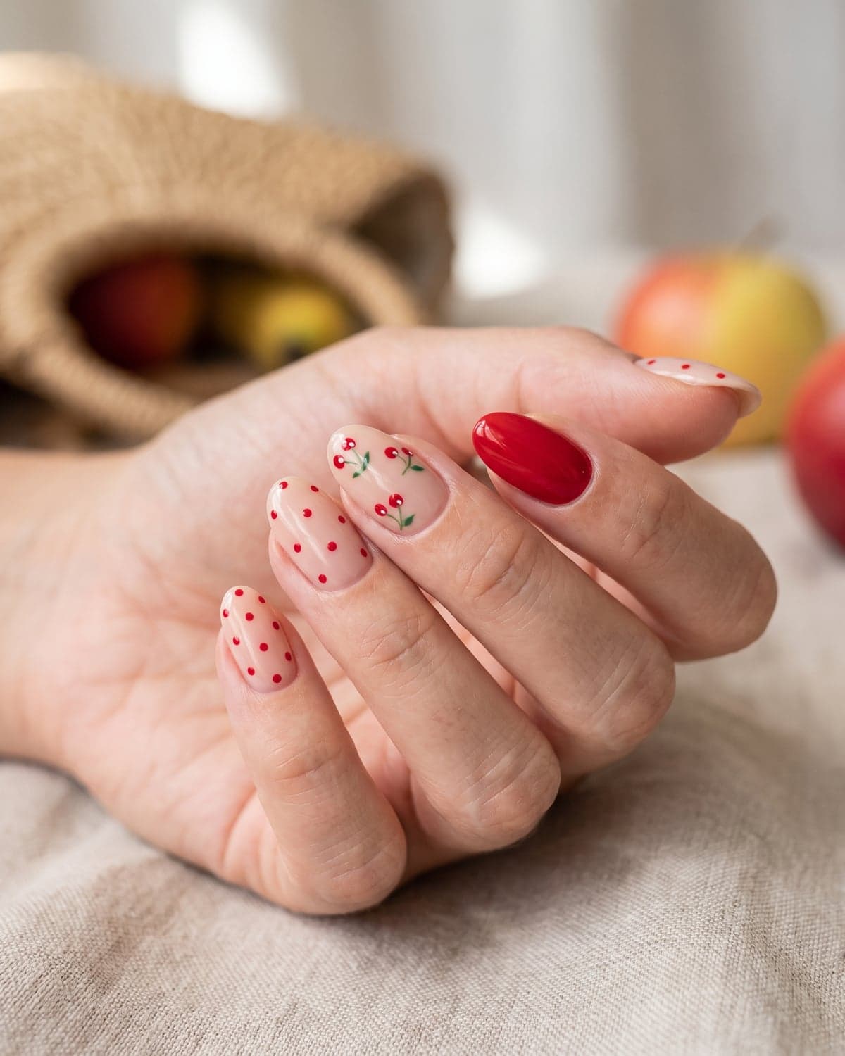 Cherry nail art on nude nails with solid red and red polka dot nails