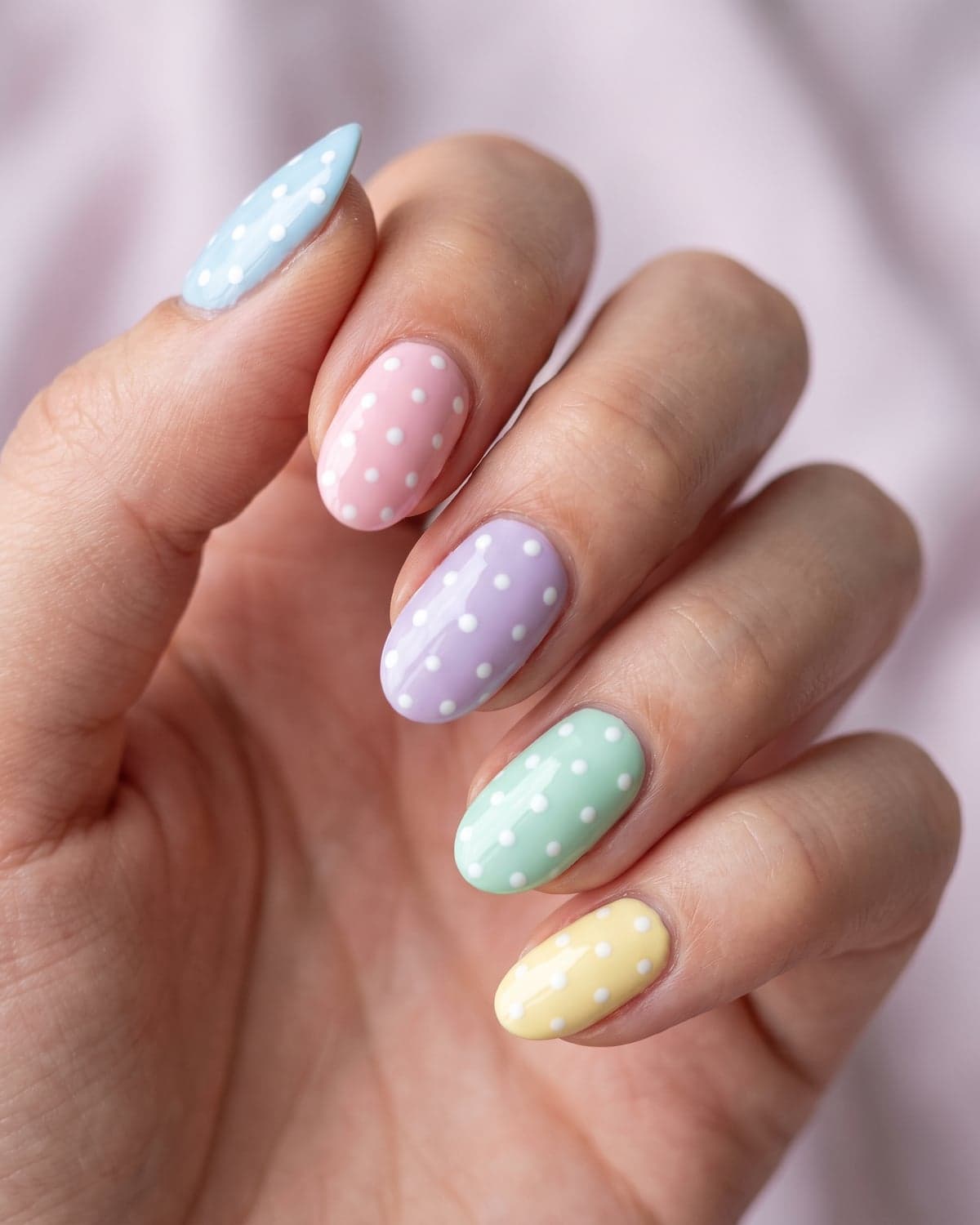 Pastel polka dot oval nails in blue, pink, lilac, mint and yellow on a soft pastel background