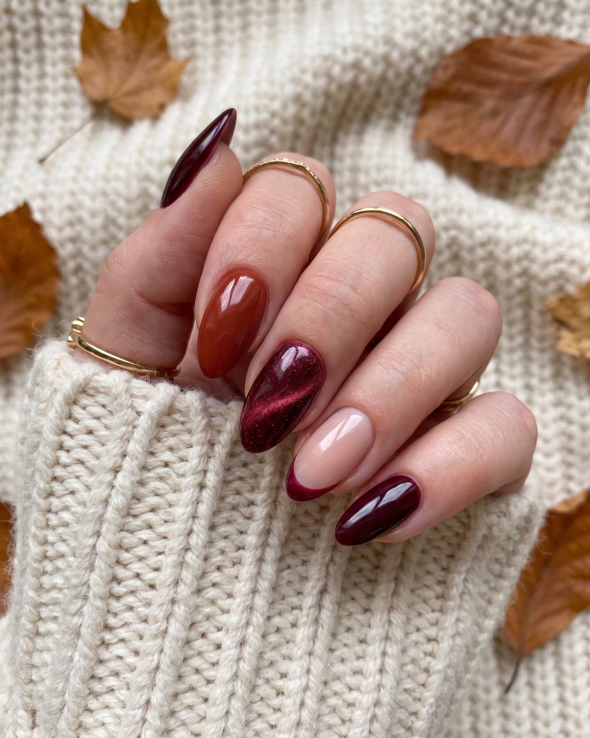 Burgundy, rust and wine velvet almond nails with a micro French accent on a warm cream background with autumn leaves