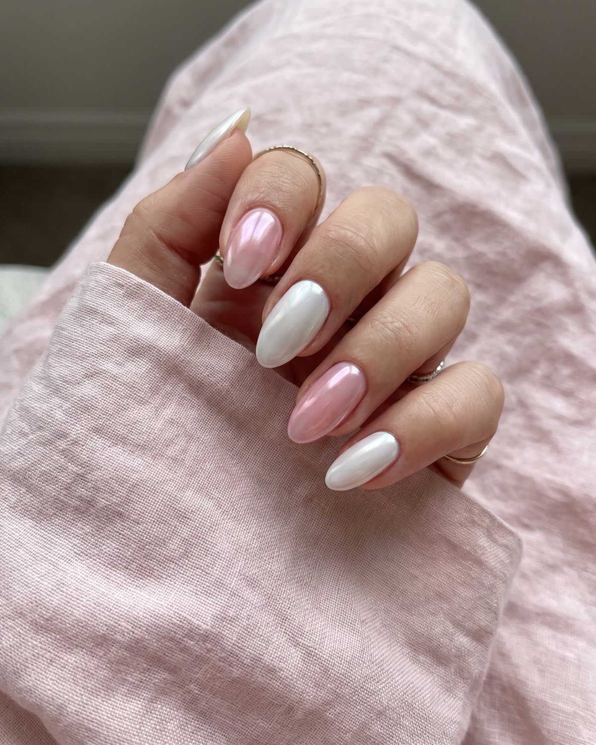 Almond nails alternating between classic white glazed donut and sheer pink strawberry glazed, on pale pink linen