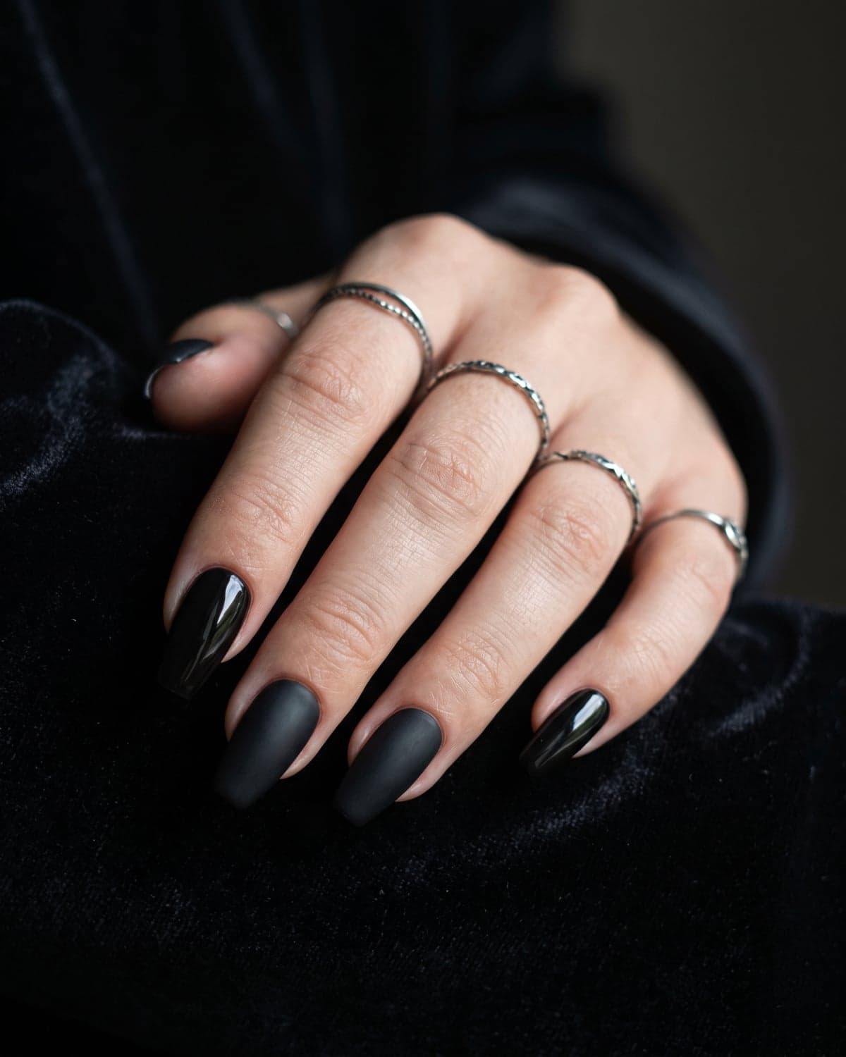 Glossy and matte black coffin nails on a dark background