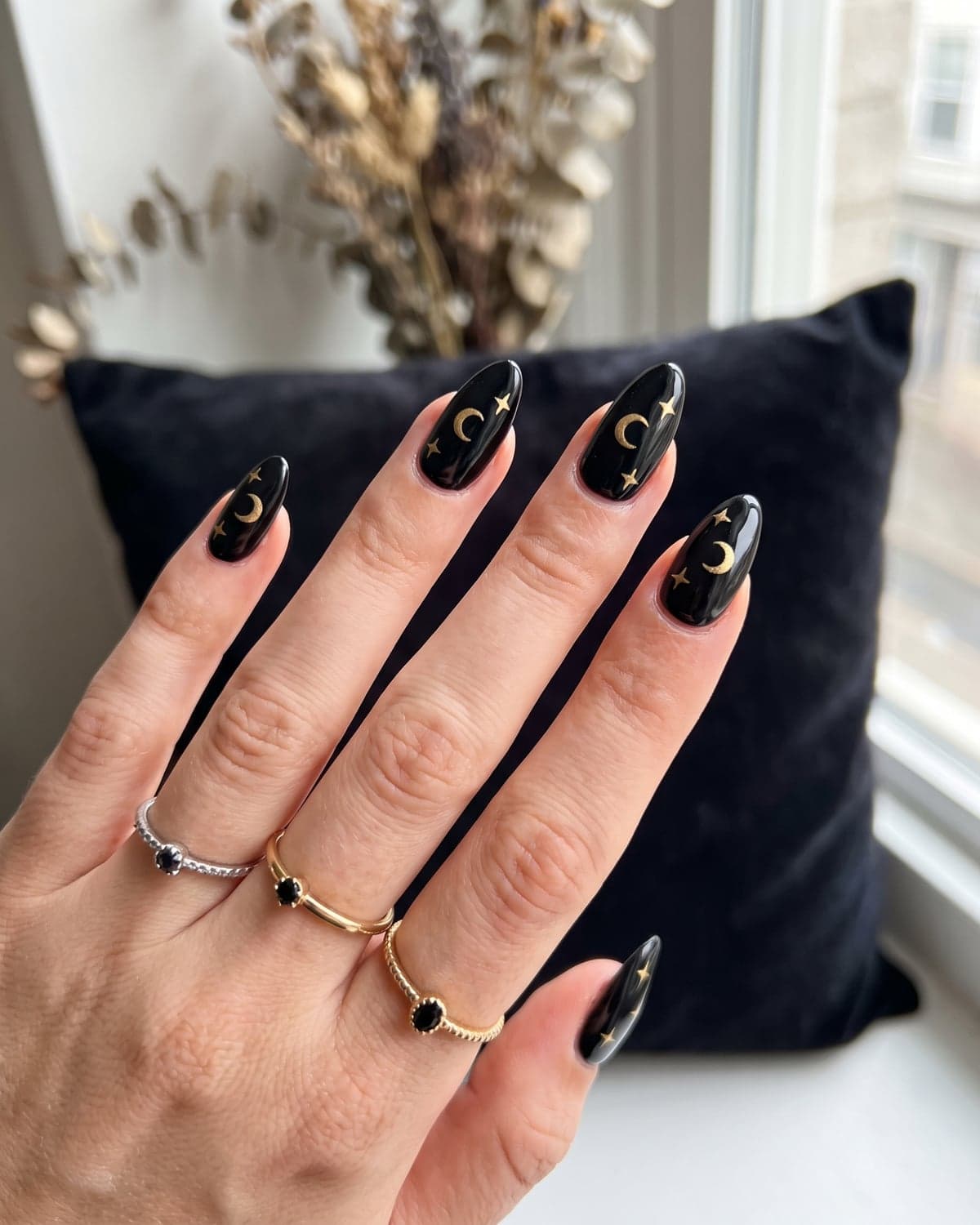 Crescent moon and star nail art in gold on black almond nails