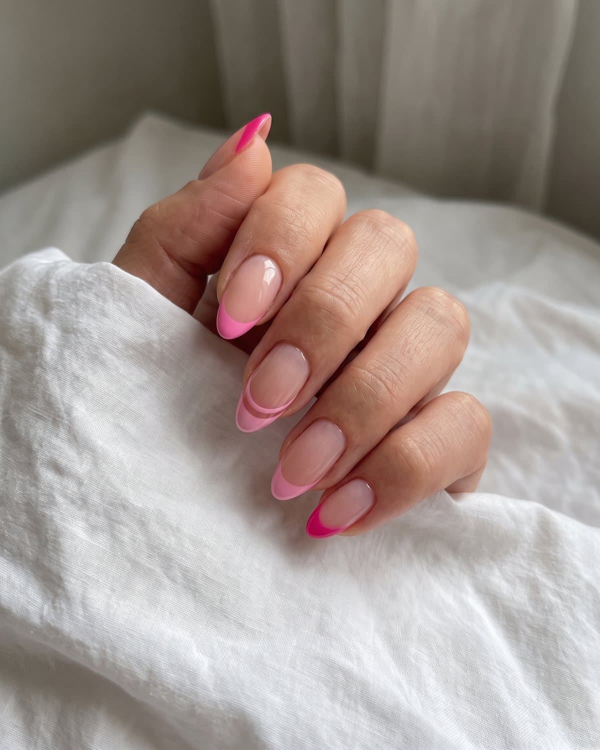 Almond nails with hot pink French tips, ultra-thin micro pink tips and pink double-line French tips, on white cotton