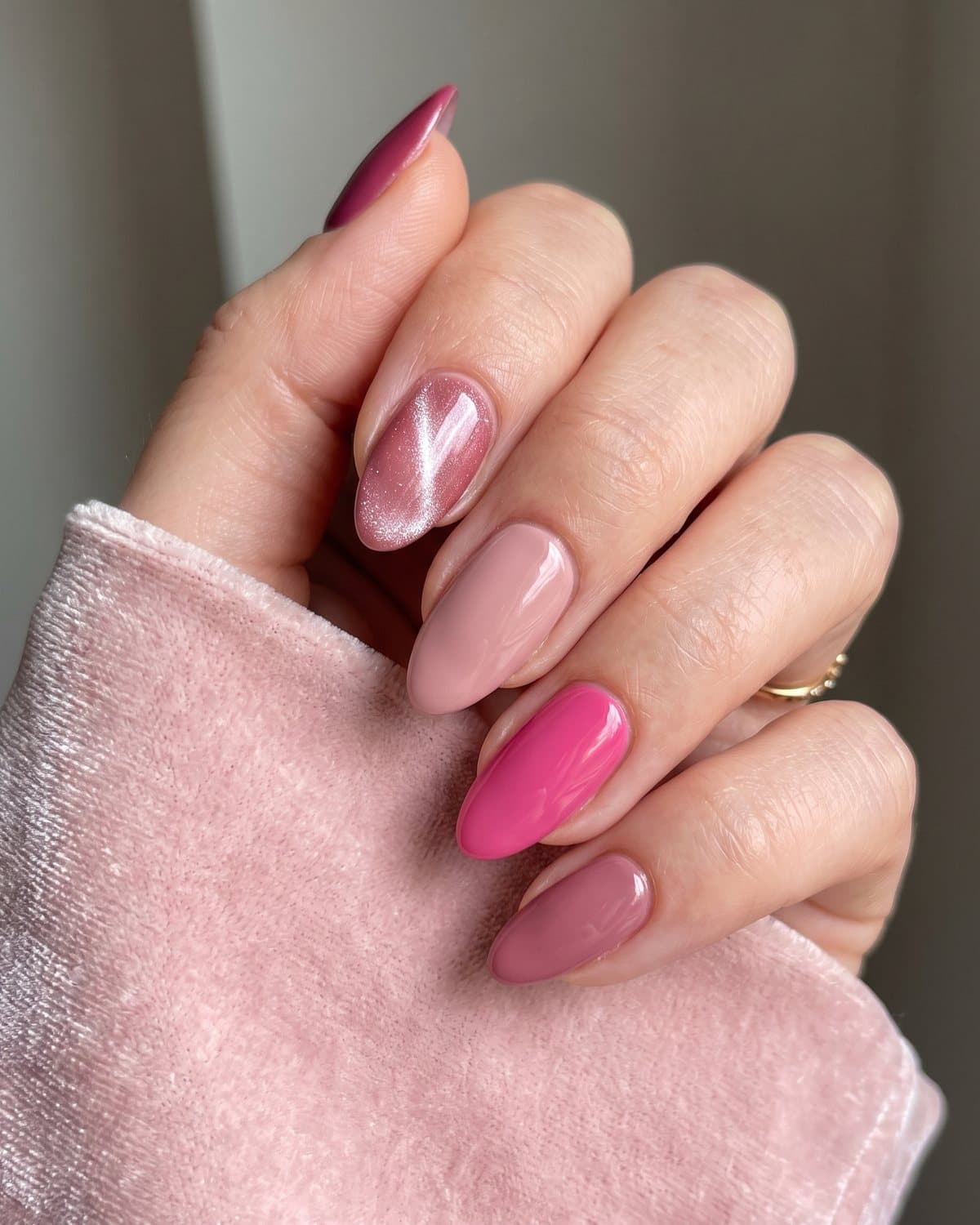 Almond nails in rose pink cat-eye shimmer mixed with mismatched pink shades from blush to fuchsia, on pale pink velvet