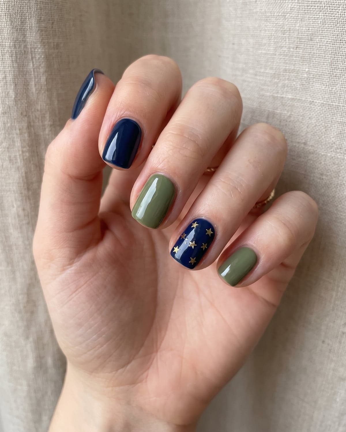 Short navy and olive green squoval nails with a starry accent nail