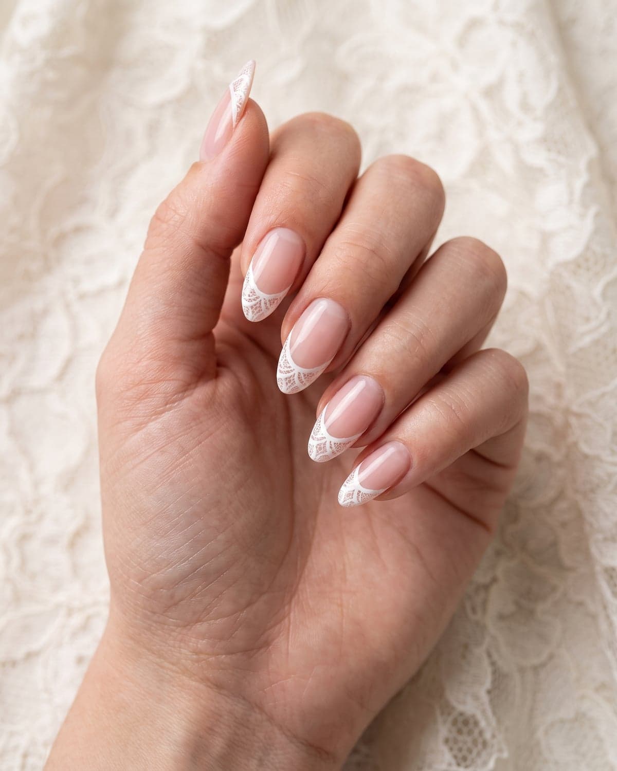 White lace French tip almond bridal nails on a sheer pink base