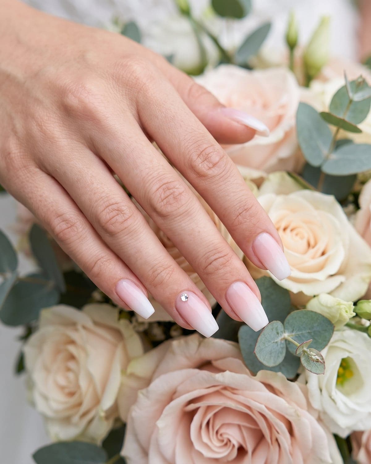 Baby boomer ombré coffin nails fading from pink to white with a crystal accent
